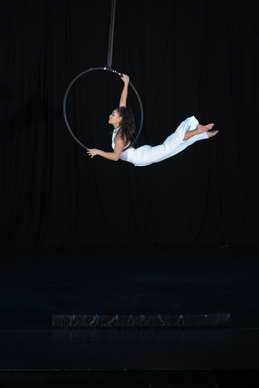 Aerial hoop performance with a female aerialist in an elegant pose