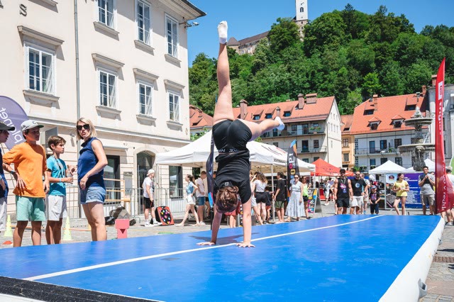 Participant in a handstand on the air track with the castle hill in the background