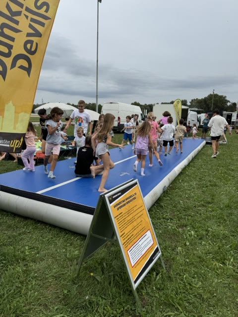 Children running and playing on the blue air track next to a safety instructions sign