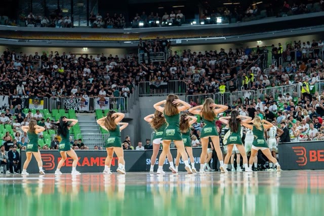 Dance team in green performing a choreography in front of a packed arena