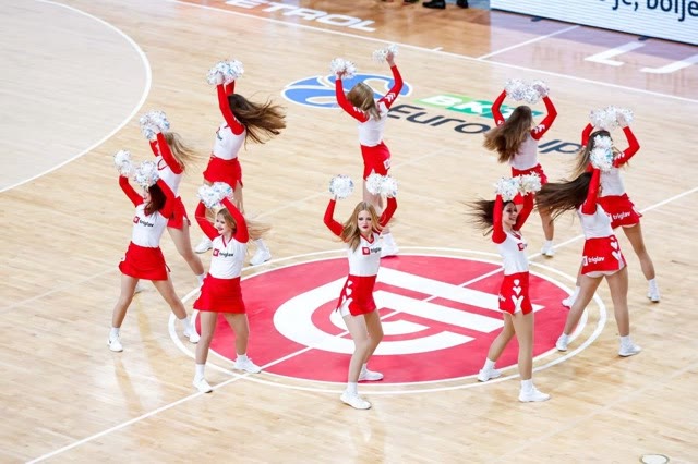 Dancers in red and white with pom-poms performing on the court's centre circle