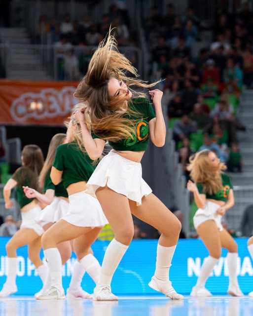 Dancer in a green top and white skirt with flying hair during a performance