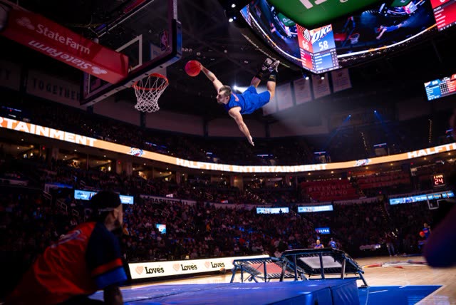 Athlete in a blue kit flying horizontally towards the hoop in an NBA arena