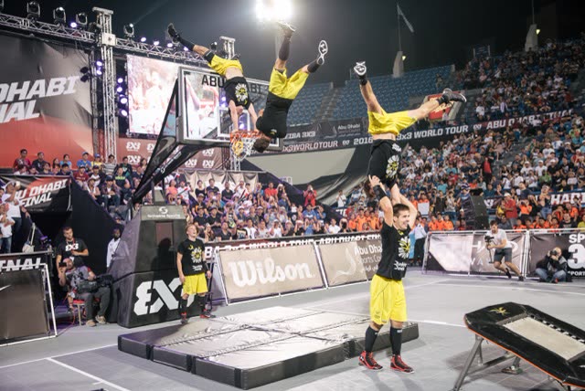 Athletes in a stacked formation flipping upside down towards the hoop at a FIBA 3x3 final