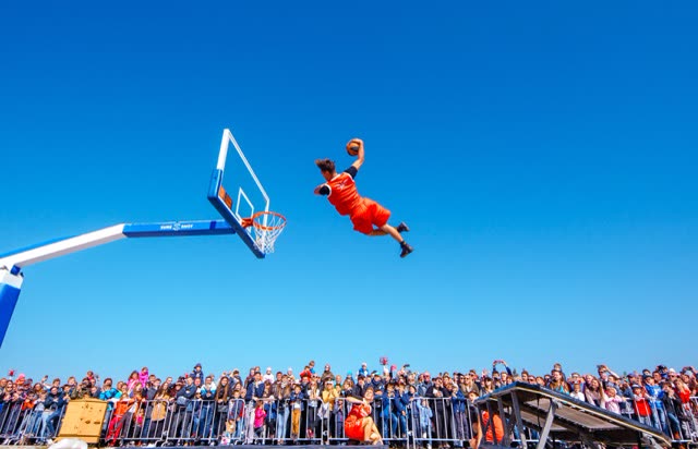 Acrobat flying high above a cheering crowd at an outdoor event