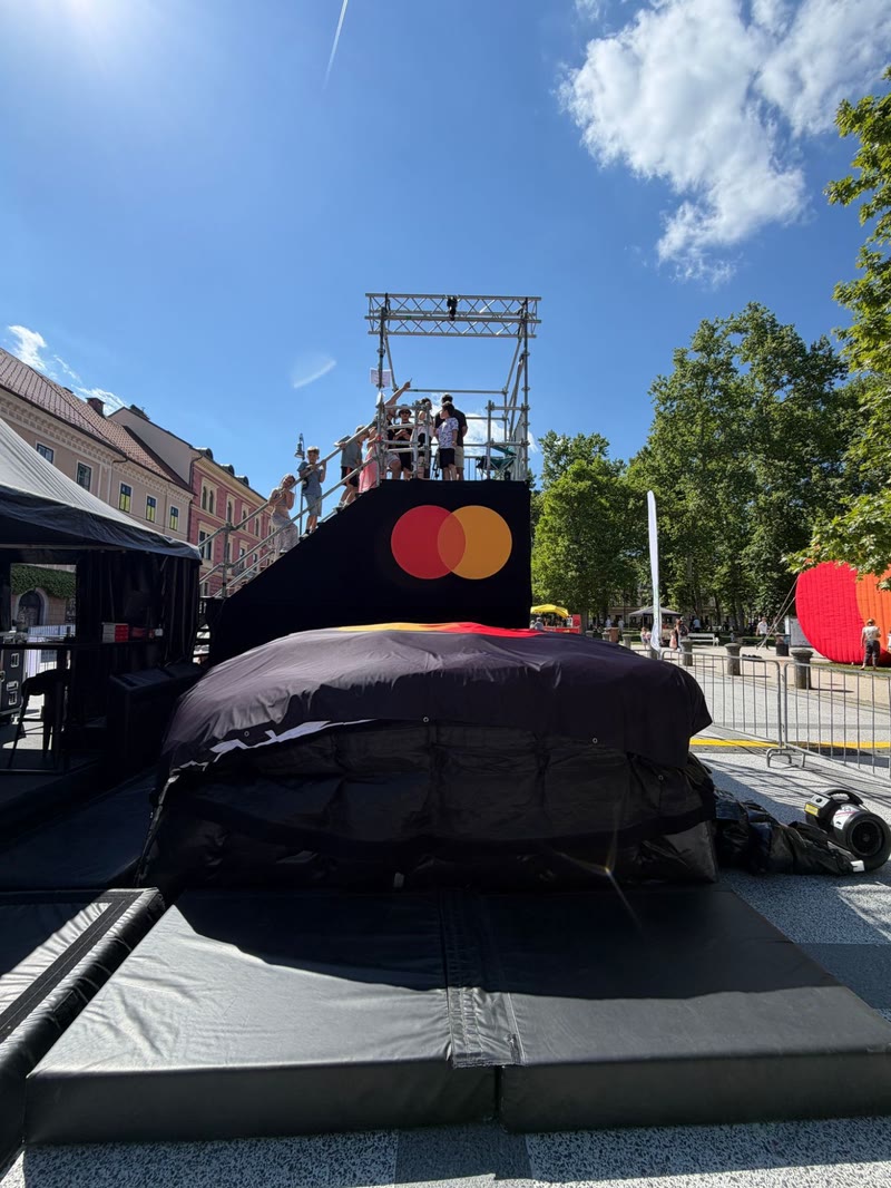 Black airbag with a branded jump tower and visitors queuing on the stairs on a city square