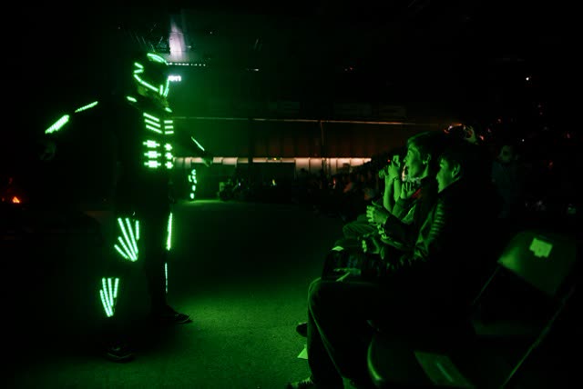 LED dancer in a green glowing costume performing next to the audience at a close-up event