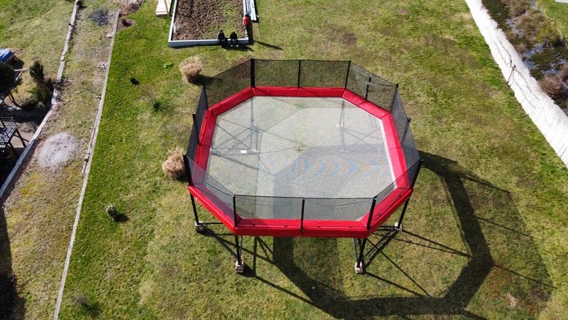 Aerial view of the octagonal red Megatramp with safety nets on a lawn