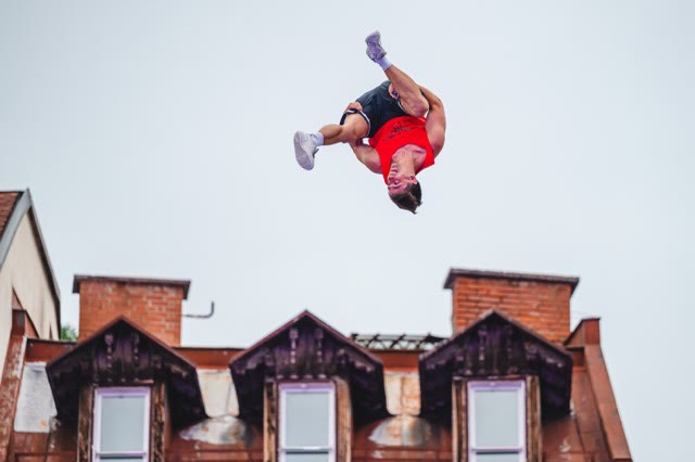 Acrobat upside down in a flip above the roofs of old town houses