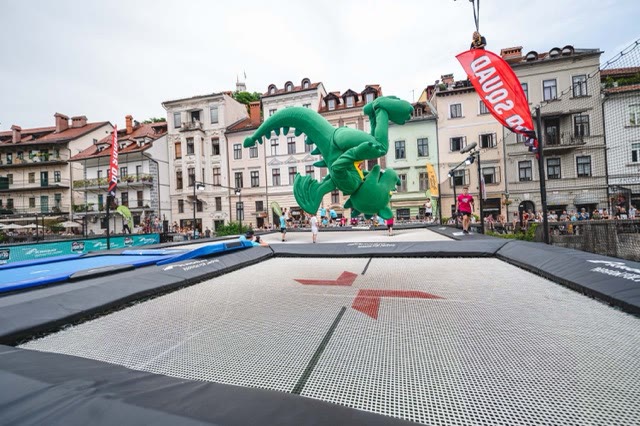 Giant green inflatable dragon floating above the trampoline in a Ljubljana square