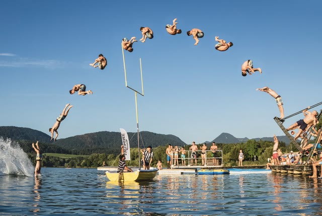 Sequence of flips from the russian swing over a lake with people watching from boats and platforms