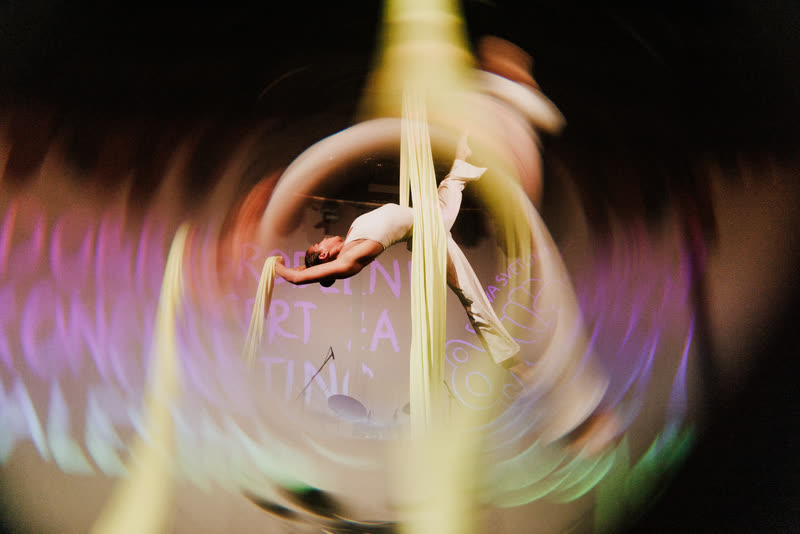 Artistic long-exposure photo of an aerialist spinning on aerial silks