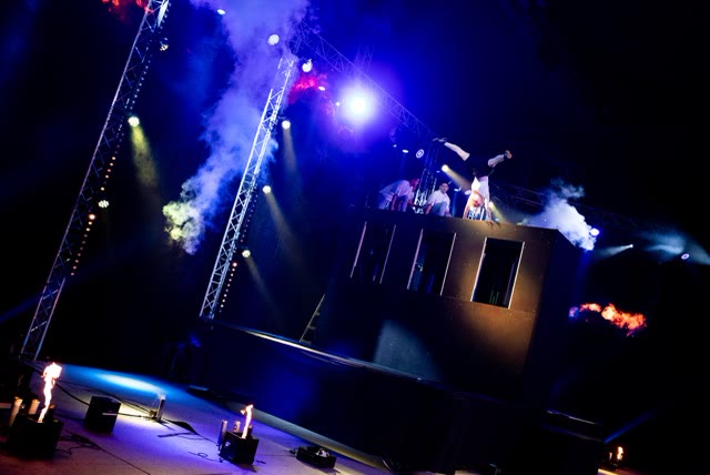 Acrobat in a handstand on top of the trampoline wall on a smoky blue-lit stage